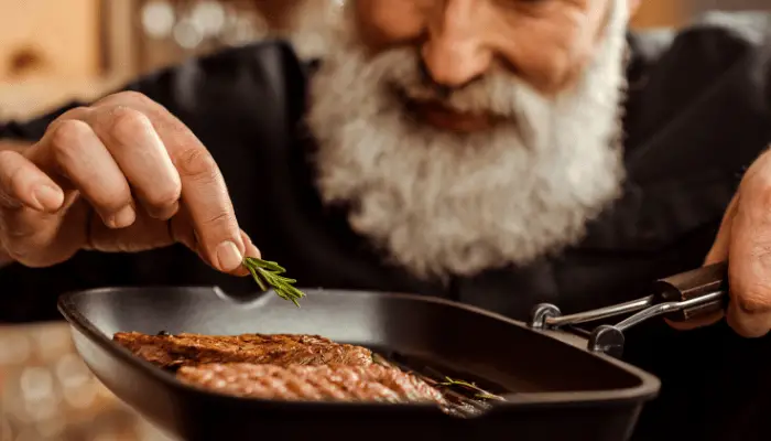 man cooking steak in the frying pan